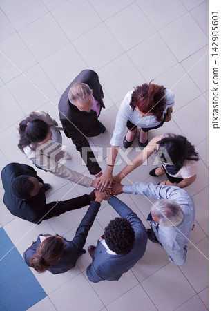 Business team standing in a circle with hands together showing teamwork and collaboration Business team standing in a circle with hands together showing teamwork and collaboration 142905601
