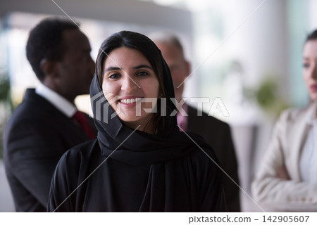 Businesswoman in hijab smiling confidently in a multicultural corporate team with colleagues in background Businesswoman in hijab smiling confidently in a multicultural corporate team with colleagues in background 142905607