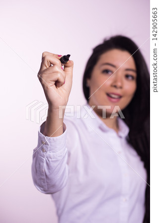 Businesswoman presenting with a marker writing on a whiteboard during a professional meeting or training session Businesswoman presenting with a marker writing on a whiteboard during a professional meeting or training session 142905663