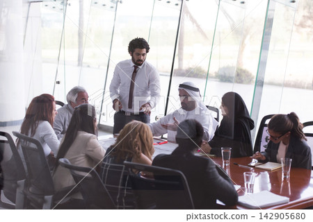 Business meeting with multicultural team discussing strategy around a glass conference table Business meeting with multicultural team discussing strategy around a glass conference table 142905680