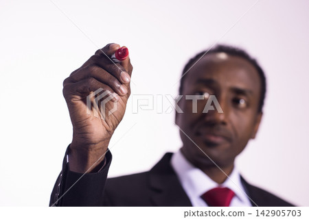 Businessman writing with a red marker during a corporate presentation and strategic planning session Businessman writing with a red marker during a corporate presentation and strategic planning session 142905703