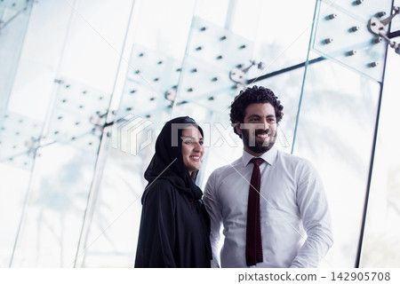 Smiling professional colleagues in a modern office with woman wearing hijab and male business partner Smiling professional colleagues in a modern office with woman wearing hijab and male business partner 142905708