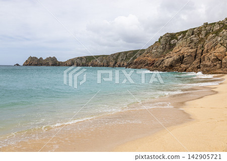 Sandy beach and turquoise sea by coastal cliffs Sandy beach and turquoise sea by coastal cliffs 142905721