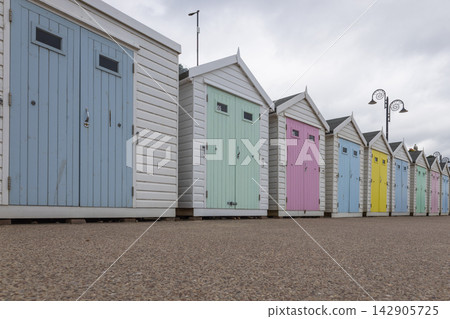 Colorful wooden beach huts in a row by seaside 142905725