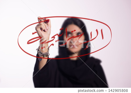 Middle Eastern businesswoman writing 'strategy' in Arabic on glass with red marker for planning Middle Eastern businesswoman writing 'strategy' in Arabic on glass with red marker for planning 142905808