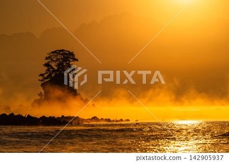 The sunrise and the sea bathed in golden hues at dawn, as seen from Amaharashi Coast in Toyama. The sunrise and the sea bathed in golden hues at dawn, as seen from Amaharashi Coast in Toyama. 142905937
