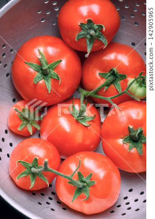 Red tomatoes with stems in metal bowl 142905965