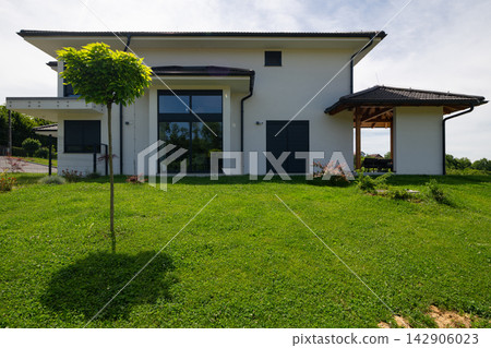Modern minimalist two-story house with green lawn and low-energy design emphasizing efficiency Modern minimalist two-story house with green lawn and low-energy design emphasizing efficiency 142906023