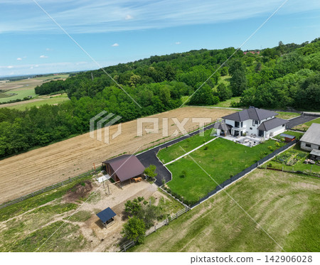 Aerial view of a modern modular country house with low-energy design and solar panels in fields Aerial view of a modern modular country house with low-energy design and solar panels in fields 142906028