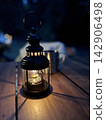 An oil lantern illuminates the wooden table at night. 142906498