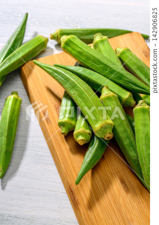 Fresh okra arranged on a wooden cutting board Fresh okra arranged on a wooden cutting board 142906825