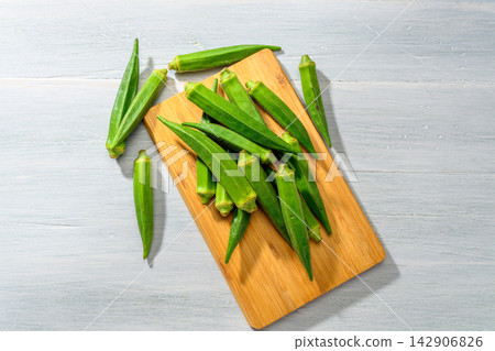 Fresh okra arranged on a wooden cutting board 142906826