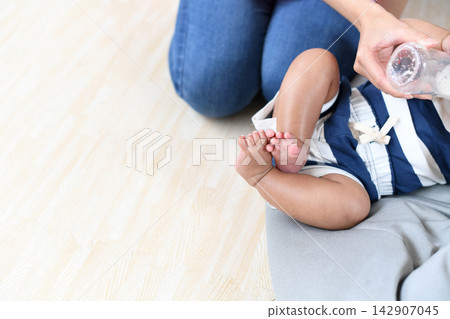 一個6個月大的嬰兒正在用奶瓶喝奶。 一個6個月大的嬰兒正在用奶瓶喝奶。 142907045