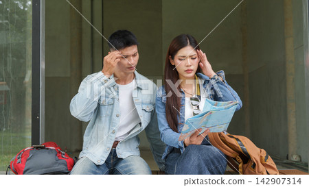 Asian tourist couple looking at map with stressed confused expression while lost on trip 142907314