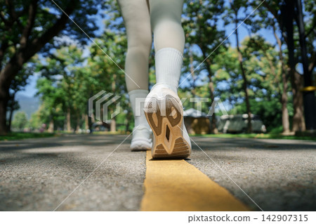 Low angle view of person walking on park road for active fitness lifestyle 142907315