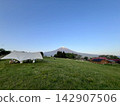 A grassy campsite with a view of Mt. Fuji and a blue sky. 142907506