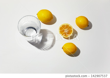 Fresh lemons and water glass casting shadows Fresh lemons and water glass casting shadows 142907537