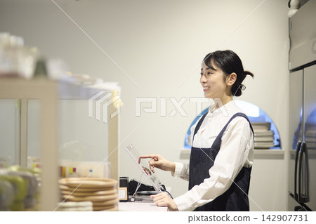 Female staff member using cashless payment at cafe Female staff member using cashless payment at cafe 142907731