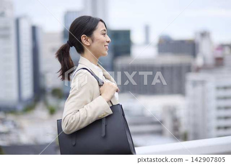 一位微笑的女商人走在上班的路上。 一位微笑的女商人走在上班的路上。 142907805