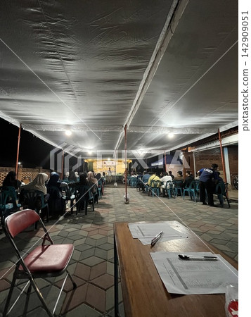 Under a large tent, a community gathers for an event Under a large tent, a community gathers for an event 142909051