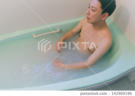 A man in his 40s taking a bath in his home bathroom. A man in his 40s taking a bath in his home bathroom. 142909196