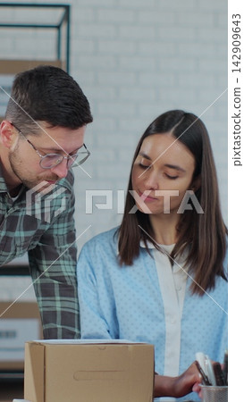 Vertical video. Warehouse Work: Woman on Computer, Man Checking Boxes. 142909643