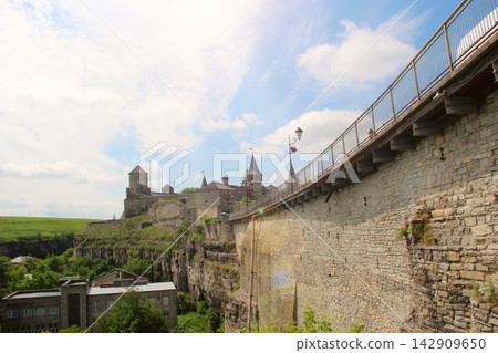 Kamianets-Podilskyi castle and old bridge view under a blue cloudy sky. Kamianets-Podilskyi castle and old bridge view under a blue cloudy sky. 142909650