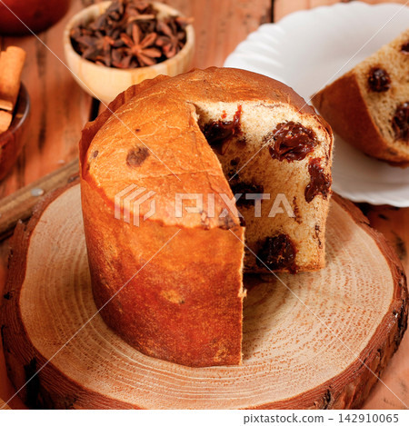 Sliced chocolate panettone served as a special dessert on a rustic wooden table. Sliced chocolate panettone served as a special dessert on a rustic wooden table. 142910065