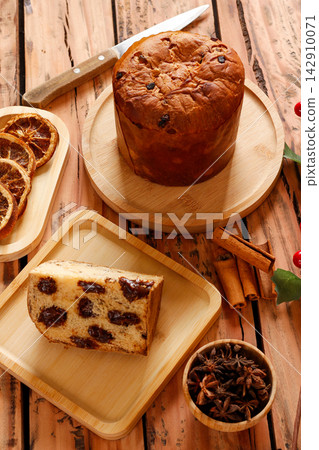 Chocolate panettone served during Christmas festivities on a rustic wooden table with traditional decorations. 142910071