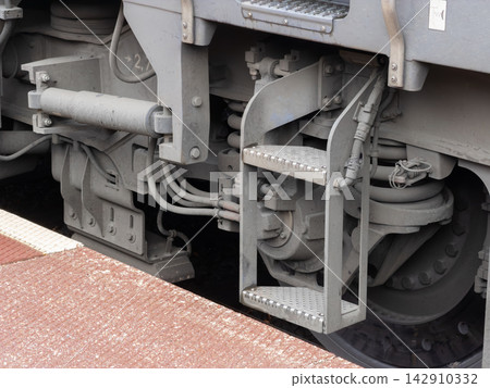 A close view of a metal access ladder attached to a heavy industrial train bogie, emphasizing railway maintenance engineering and the robust mechanical design of transit systems A close view of a metal access ladder attached to a heavy industrial train bogie, emphasizing railway maintenance engineering and the robust mechanical design of transit systems 142910332