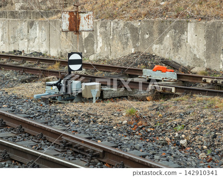A railroad switch signal stands near metal train tracks with industrial gravel bedding, depicting classic railway infrastructure for transport logistics and transit route safety 142910341