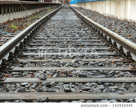 Railroad tracks stretching into the horizon on a stone railway bed, representing a perspective view of transportation infrastructure and the journey of modern travel and logistics Railroad tracks stretching into the horizon on a stone railway bed, representing a perspective view of transportation infrastructure and the journey of modern travel and logistics 142910345