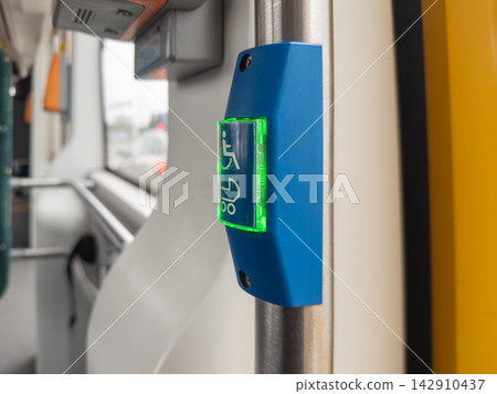A blue accessible stop button glows green on a stainless steel pole inside a public transport vehicle, highlighting inclusive mobility design for passengers with limited movement A blue accessible stop button glows green on a stainless steel pole inside a public transport vehicle, highlighting inclusive mobility design for passengers with limited movement 142910437