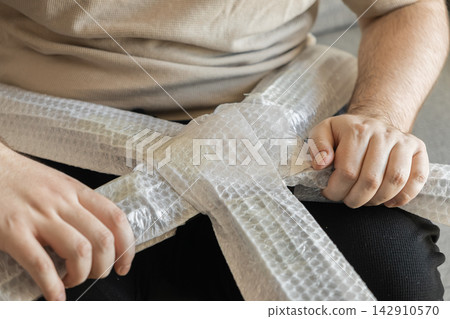 A person wrapping furniture components in protective bubble plastic film, ensuring safety and damage prevention during the relocation process of moving house for a residential project A person wrapping furniture components in protective bubble plastic film, ensuring safety and damage prevention during the relocation process of moving house for a residential project 142910570