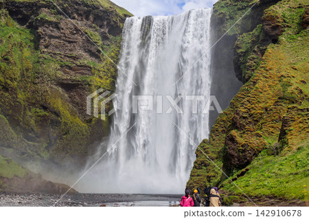 Skogafoss waterfall with mossy cliffs and visitors in the Iceland summer landscape 142910678