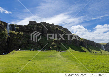 Gljufrabui waterfall and distant Seljalandsfoss above a sunny meadow in Iceland Gljufrabui waterfall and distant Seljalandsfoss above a sunny meadow in Iceland 142910753