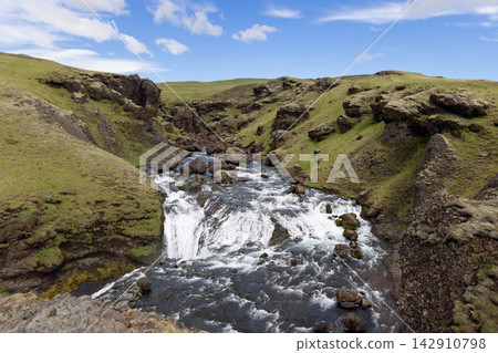 Fosstorfufoss waterfall and rocky Skoga River gorge beneath blue sky in Iceland Fosstorfufoss waterfall and rocky Skoga River gorge beneath blue sky in Iceland 142910798