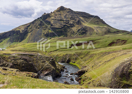 Skoga River rapids beneath a rugged mountain in a green Iceland landscape 142910800