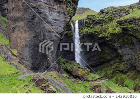 Kvernufoss waterfall framed by a massive cliff and green canyon slopes in Iceland Kvernufoss waterfall framed by a massive cliff and green canyon slopes in Iceland 142910816