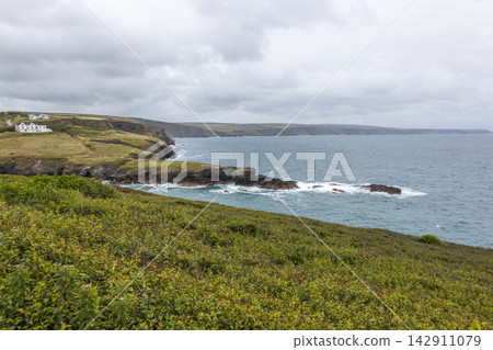 View over coastal headland with waves crashing on rocky cliffs and grassy hills View over coastal headland with waves crashing on rocky cliffs and grassy hills 142911079