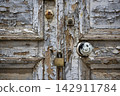 Old Padlocked Door with Peeling Paint and Weathered Wood 142911784