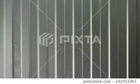 Texture of gray profiled metal sheeting with vertical ribbing. The metal sheet has a matte finish. Used for roofing, as well as the construction of fences, hangars, and partitions. Texture of gray profiled metal sheeting with vertical ribbing. The metal sheet has a matte finish. Used for roofing, as well as the construction of fences, hangars, and partitions. 142911961