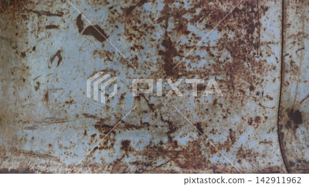 Rusty metal texture with scratches. A close-up of an old iron sheet featuring extensive orange-brown corrosion and scuff marks. A suitable grunge background for designs and collages. 142911962