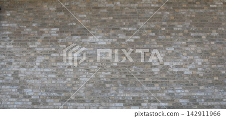 A wall made of grayish-brown decorative brick. The image shows the varied texture of the brickwork, featuring an alternation of light and dark shades. Suitable for backgrounds, textures, and construct A wall made of grayish-brown decorative brick. The image shows the varied texture of the brickwork, featuring an alternation of light and dark shades. Suitable for backgrounds, textures, and construct 142911966