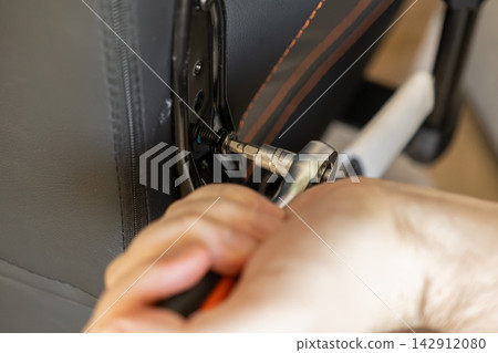 A hand uses a metal socket wrench to tighten a bolt on a black gaming chair frame, symbolizing careful furniture assembly, repair, maintenance, and expert home improvement projects A hand uses a metal socket wrench to tighten a bolt on a black gaming chair frame, symbolizing careful furniture assembly, repair, maintenance, and expert home improvement projects 142912080