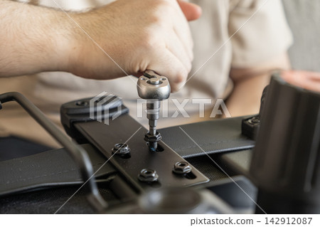 A person uses a metal ratchet wrench to tighten a bolt on a black chair frame during a DIY furniture assembly project, illustrating home repair, improvement, and task efficiency A person uses a metal ratchet wrench to tighten a bolt on a black chair frame during a DIY furniture assembly project, illustrating home repair, improvement, and task efficiency 142912087