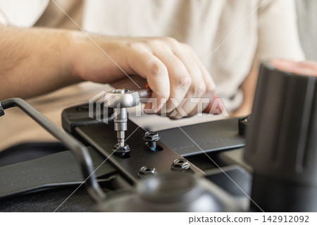 A person tightens a metal screw with a ratchet wrench on an office chair base, illustrating the process of DIY home furniture assembly for a comfortable workspace and modern comfort A person tightens a metal screw with a ratchet wrench on an office chair base, illustrating the process of DIY home furniture assembly for a comfortable workspace and modern comfort 142912092