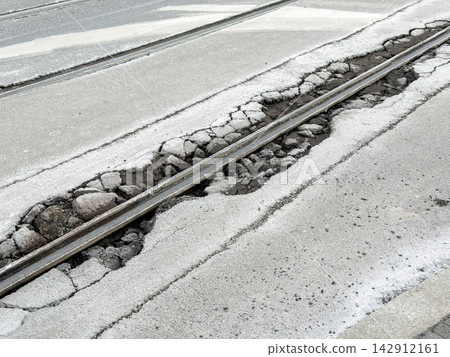 Damaged asphalt surrounding city tram tracks, highlighting dangerous road conditions, crumbling stone infrastructure, urban decay, and the urgent need for municipal maintenance repair 142912161