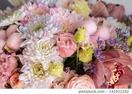 A lush floral arrangement containing soft pastel chrysanthemums, roses, and orchids creates a delicate composition for romantic celebrations or sophisticated interior decor styling A lush floral arrangement containing soft pastel chrysanthemums, roses, and orchids creates a delicate composition for romantic celebrations or sophisticated interior decor styling 142912292