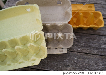 Empty colorful egg cartons on wooden table prepared for Easter craft projects Empty colorful egg cartons on wooden table prepared for Easter craft projects 142912345